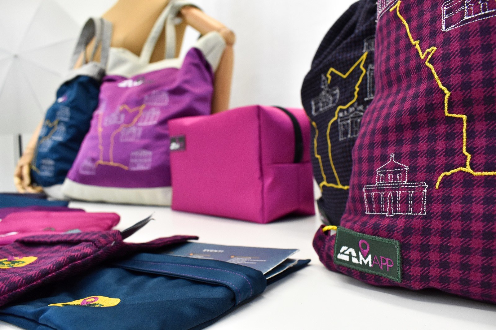 Zaini a sacca ricamati con il percorso giubilare e le chiese, il beauty case rosa e le borse in tela