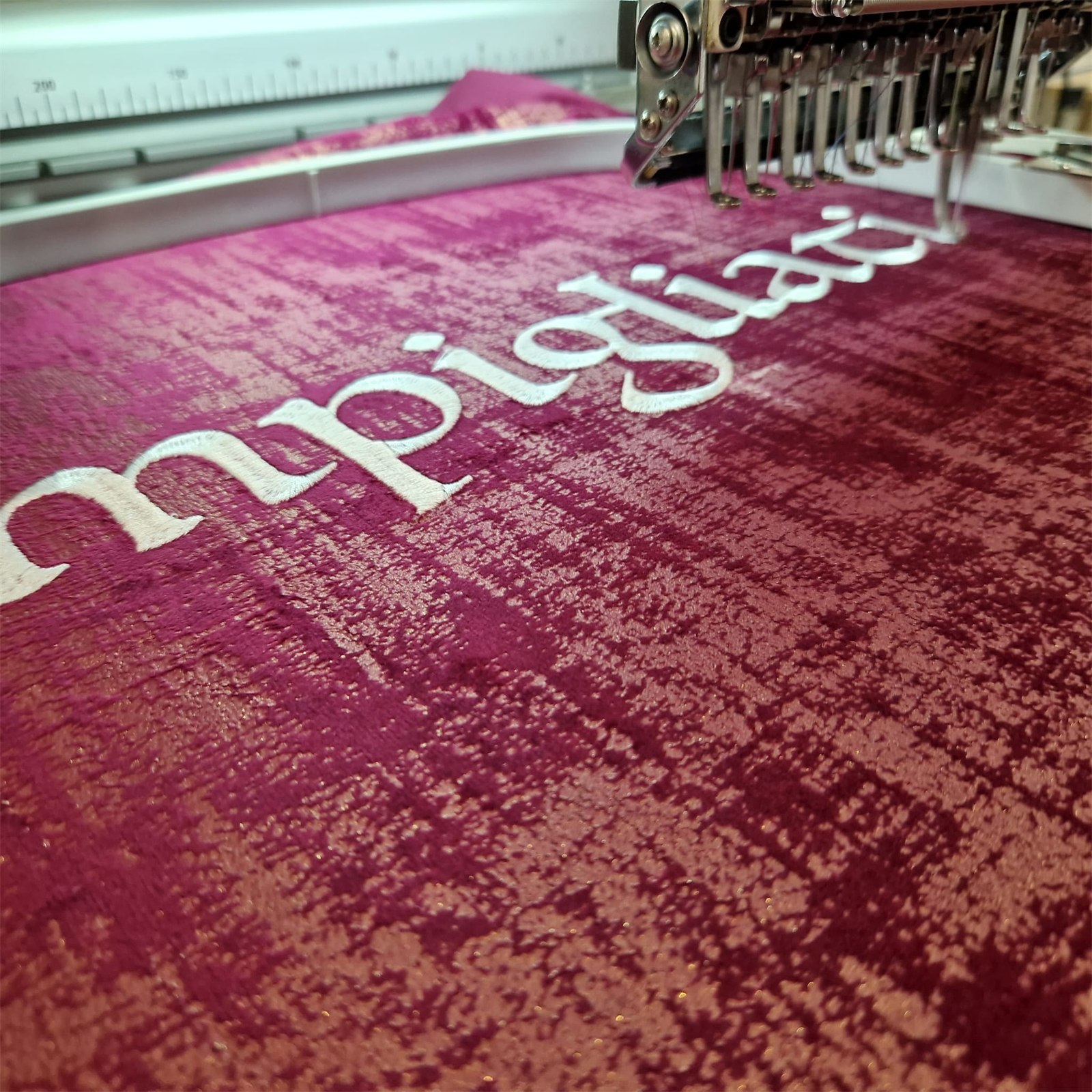 Il logo mpigliati ricamato sul velluto rosso antico, sulla macchina da ricamo del laboratorio