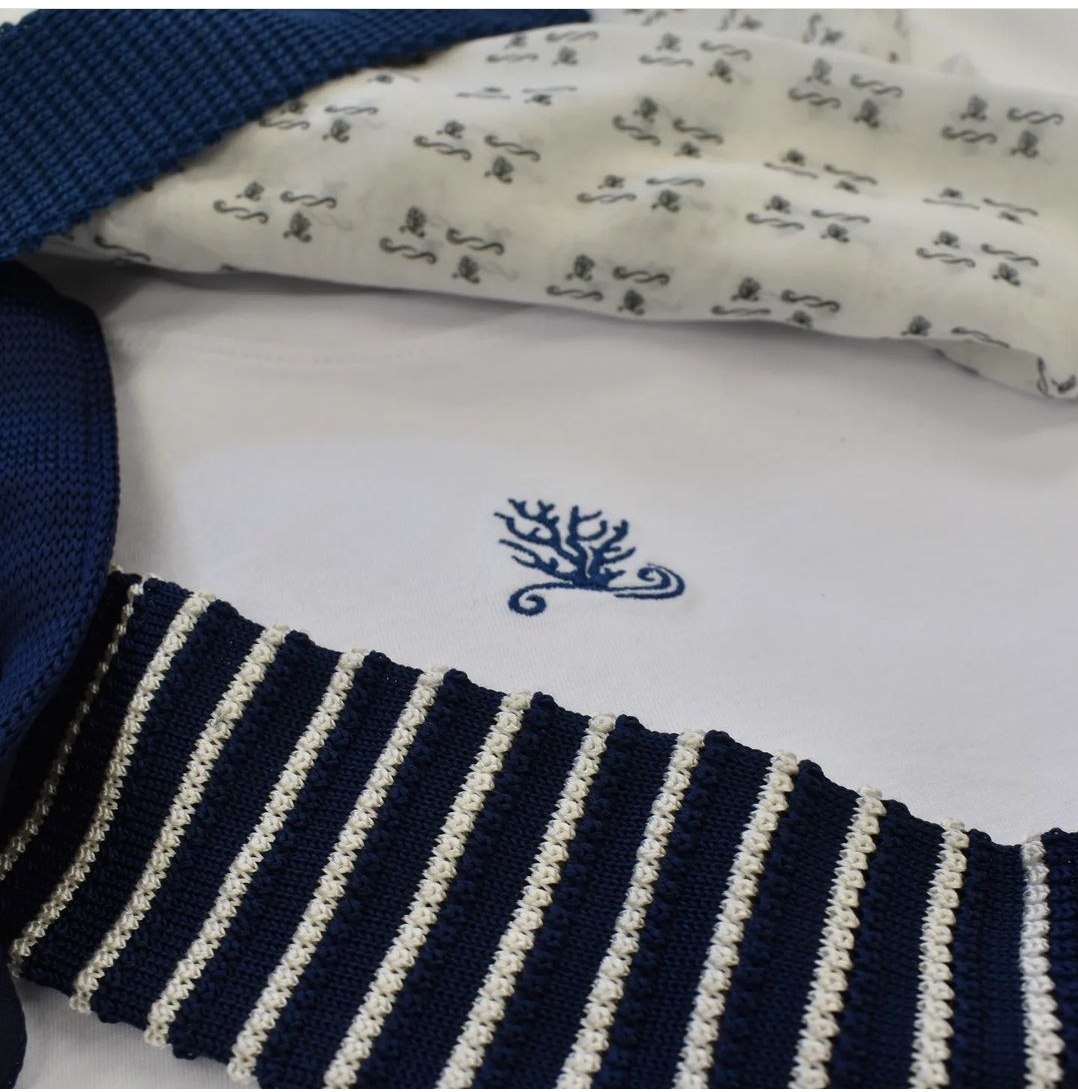 Il corallo ricamato su una t-shirt bianca con bordo a righe blu
