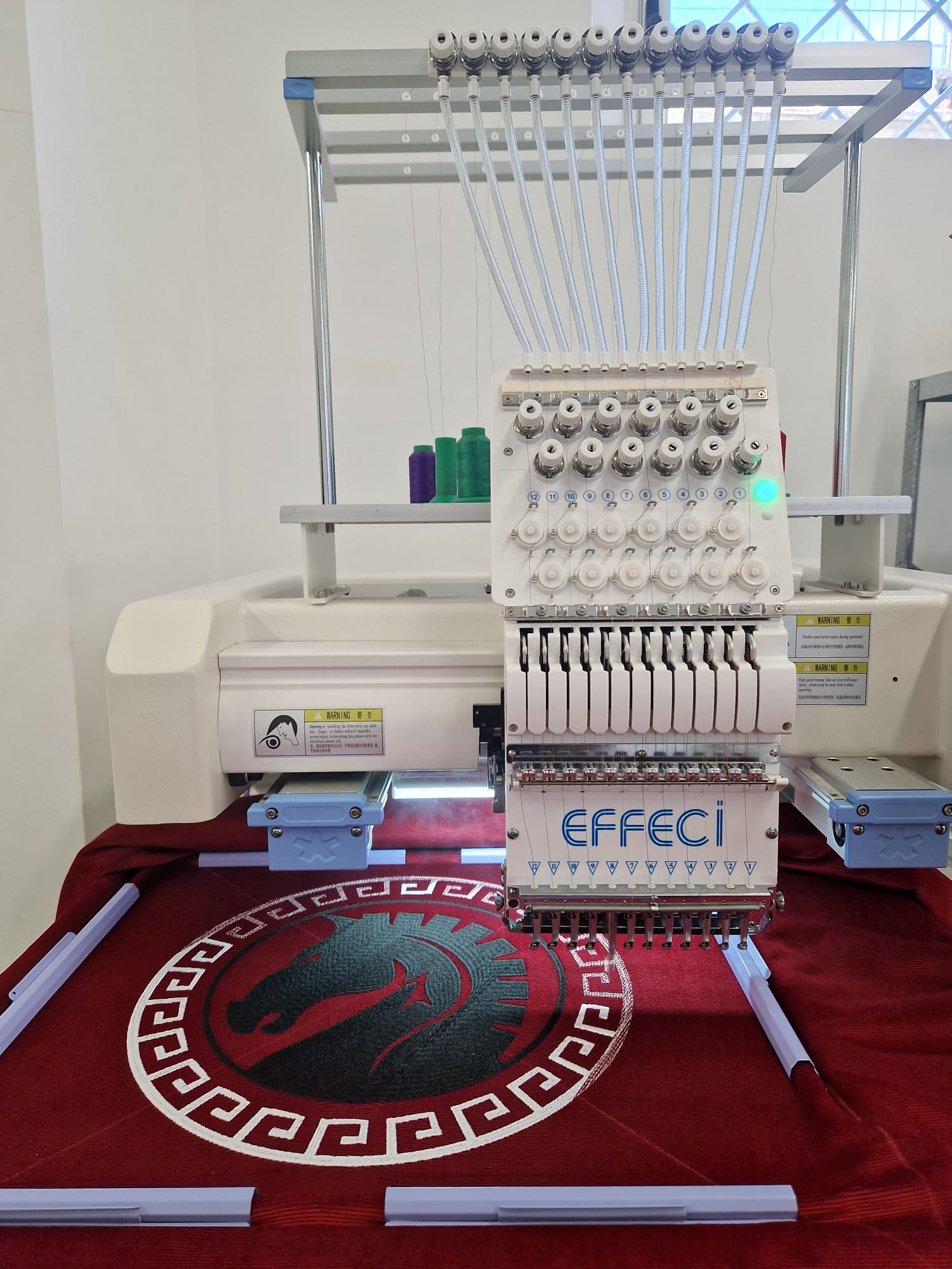 Il simbolo di Odissea Museum in ricamo sulla macchina multitesta del laboratorio